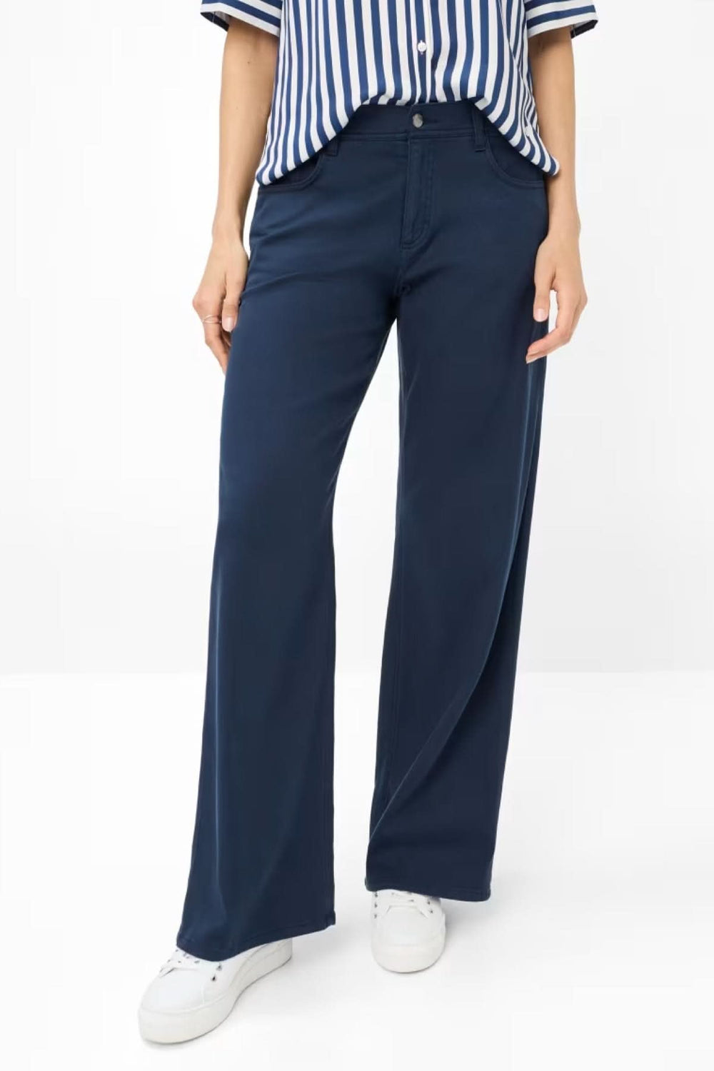 Pantalon large de style Maine, élégant et décontracté, associé à une chemise rayée et des baskets blanches.