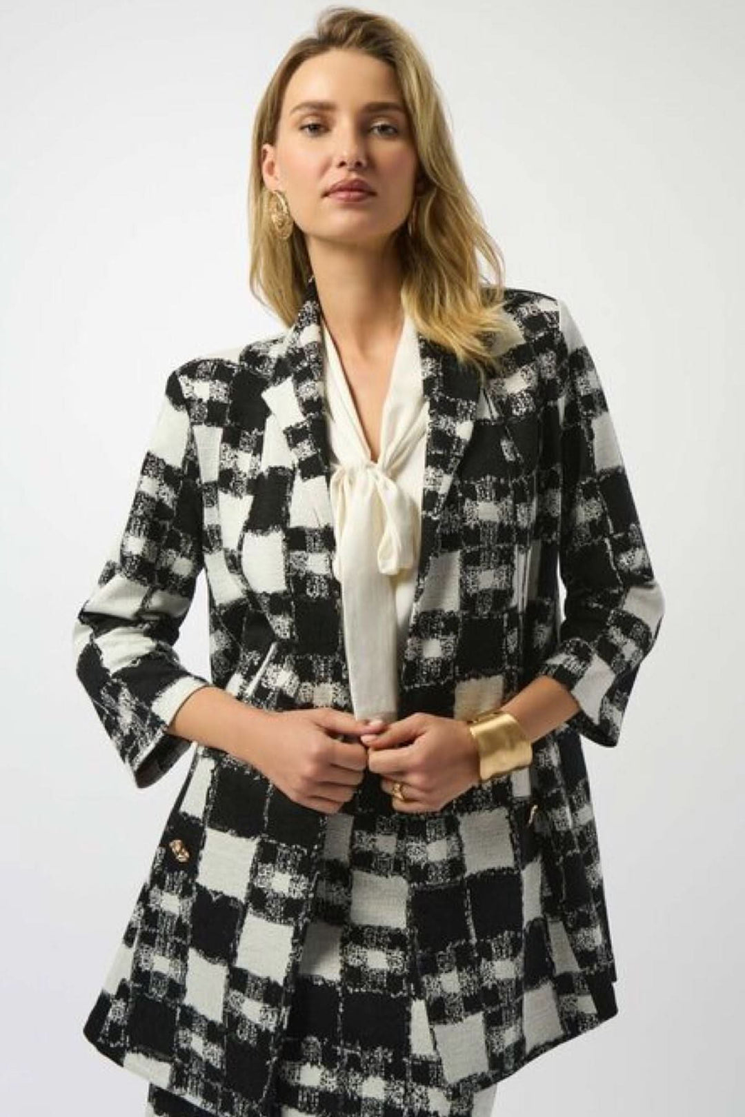 Veste longue à carreaux noir et blanc, coupe droite allongée, col à revers classique, manches 3/4.