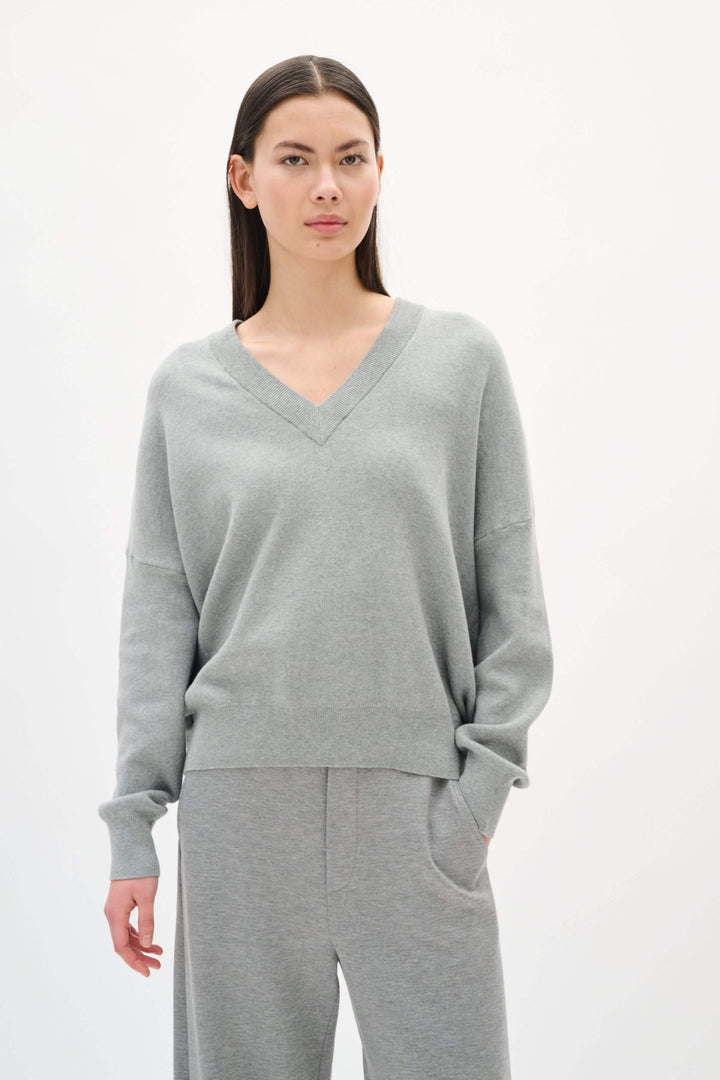 Chandail col en V gris en coton, à la coupe décontractée, avec manches longues et finitions côtelées.