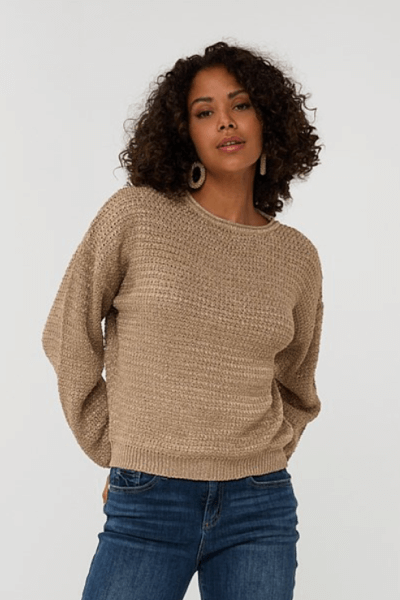 Chandail gaufré beige porté par une femme avec des boucles et des boucles d'oreilles, associé à un jean.