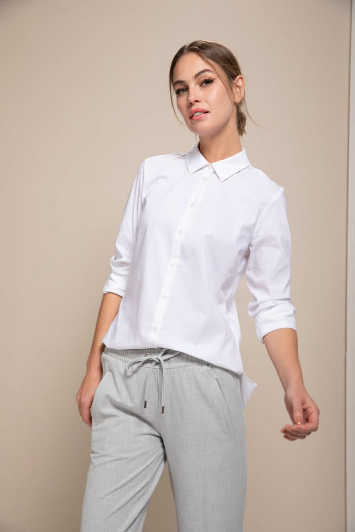 Femme portant une chemise classique blanche à manches 3/4 avec un style moderne et épuré, idéale pour le bureau ou des tenues décontractées.