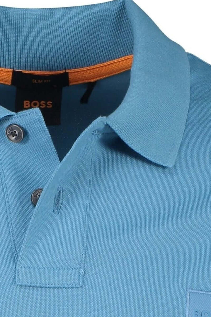 Polo bleu BOSS avec col classique, finitions ton sur ton et détail orange à l'intérieur du col.