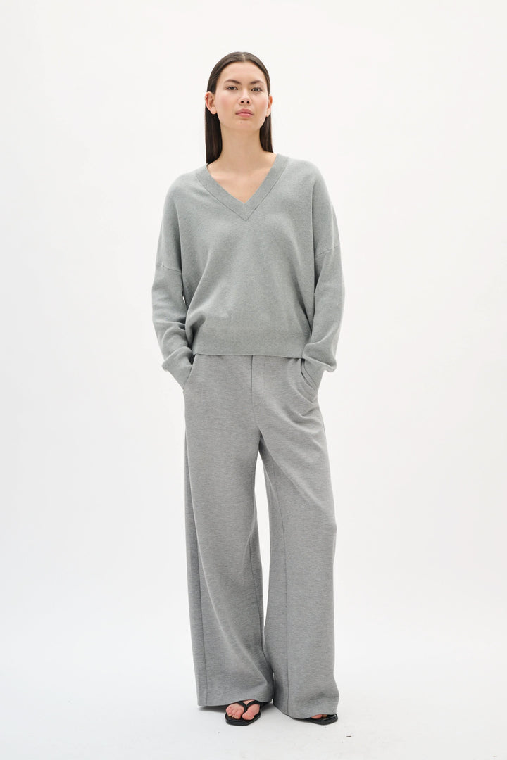 Chandail col en V Foster en coton gris, allié à un pantalon large, offrant une allure moderne et décontractée.