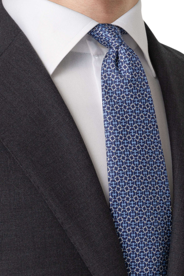 Cravate à motif géométrique bleu, ajoutant modernité à un costume formel avec chemise blanche.