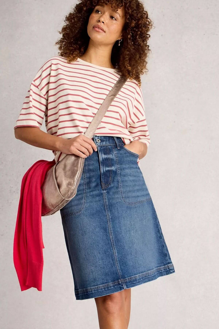 Femme portant la Jupe Tia en denim bleu avec un t-shirt rayé et un sac bandoulière, style casual chic