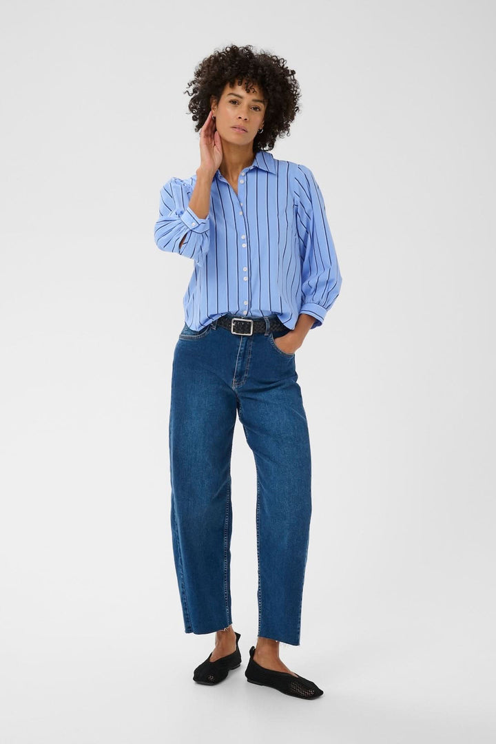 Modèle portant la Blouse rayée Anais avec col structuré et manches bouffantes, associée à un jean pour un look élégant et moderne.