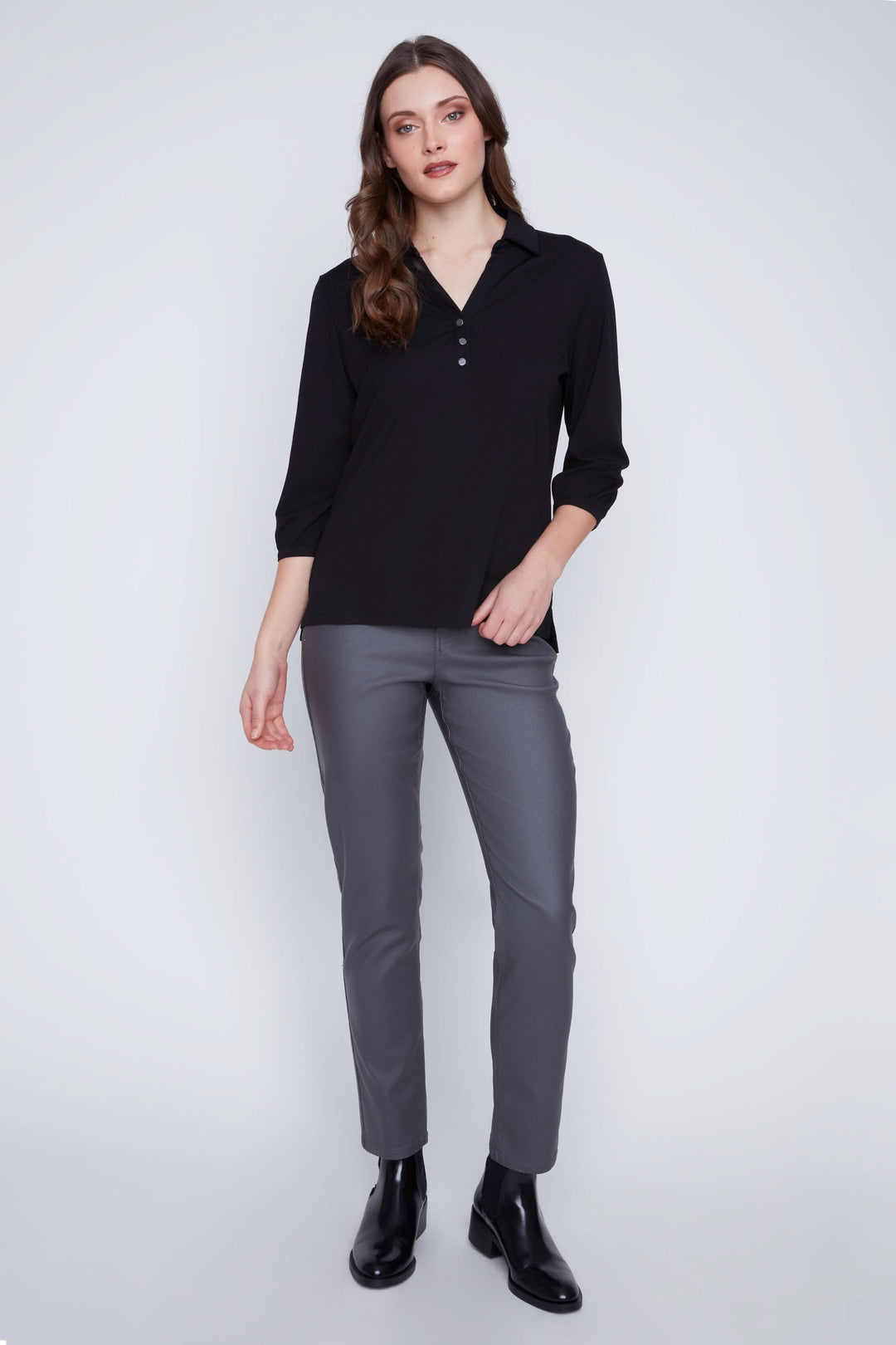 Blouse à manches 3/4 noire avec encolure en V et trois boutons portée avec pantalon ajusté.