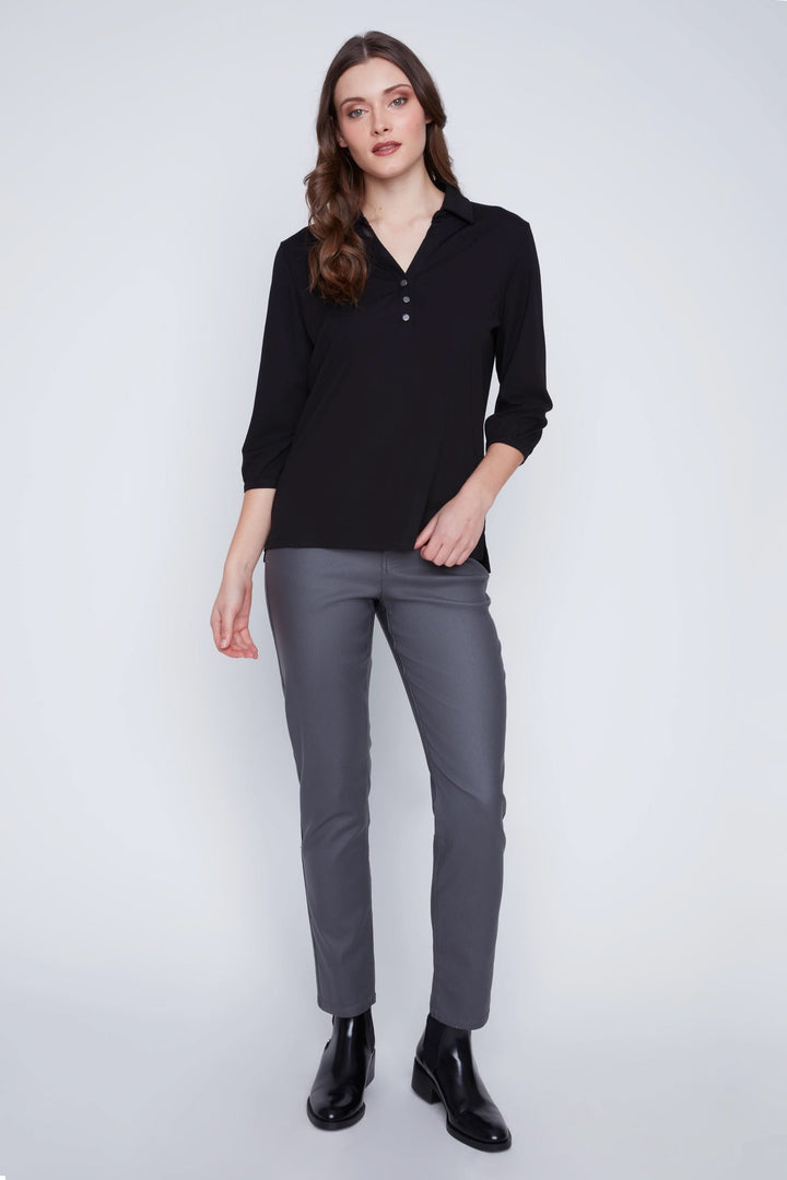 Blouse à manches 3/4 noire avec encolure en V et trois boutons portée avec pantalon ajusté.