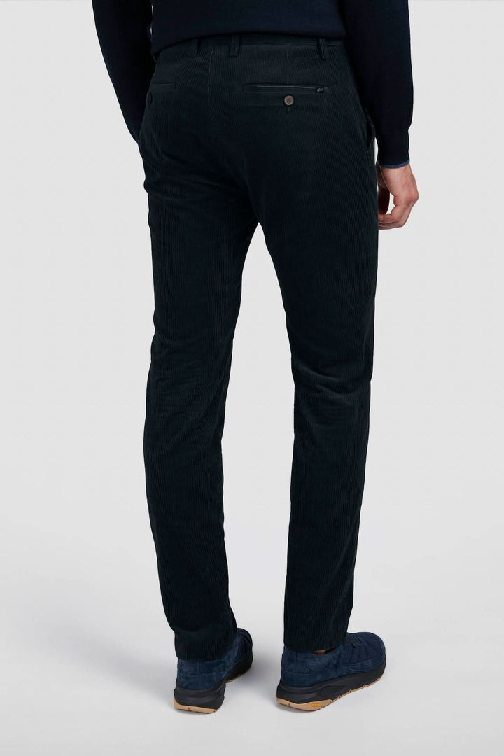 Pantalon en corduroy à côtes larges, coupe élégante, porté avec un chandail, coloris vert foncé.