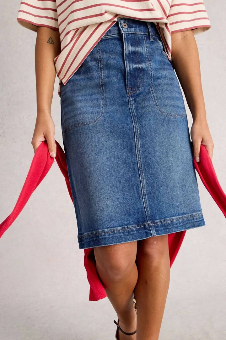 Jupe Tia en denim classique, coupe droite, taille haute, associée à un style casual chic avec T-shirt et baskets.