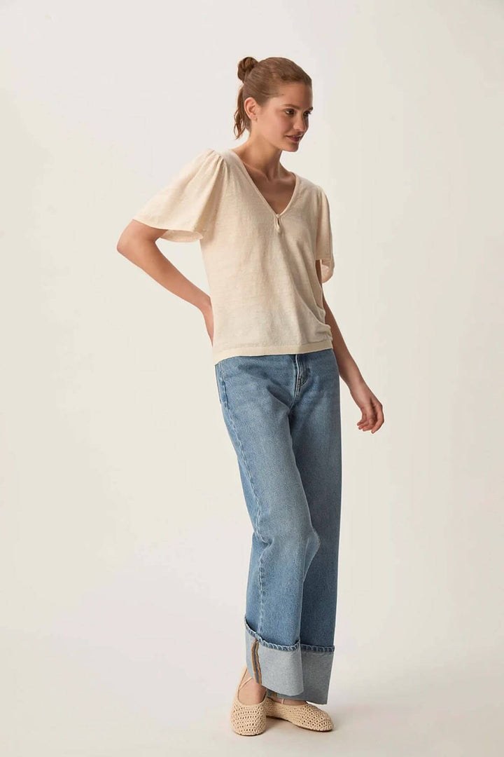 Modèle portant un pull léger à encolure en V et manches bouffantes, associé à un jean décontracté.