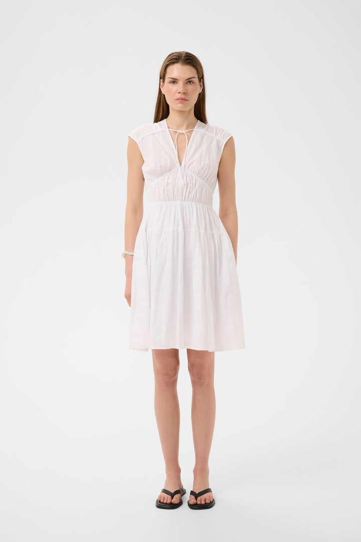 Pink, short, flowing dress with gathered details and a tied neckline