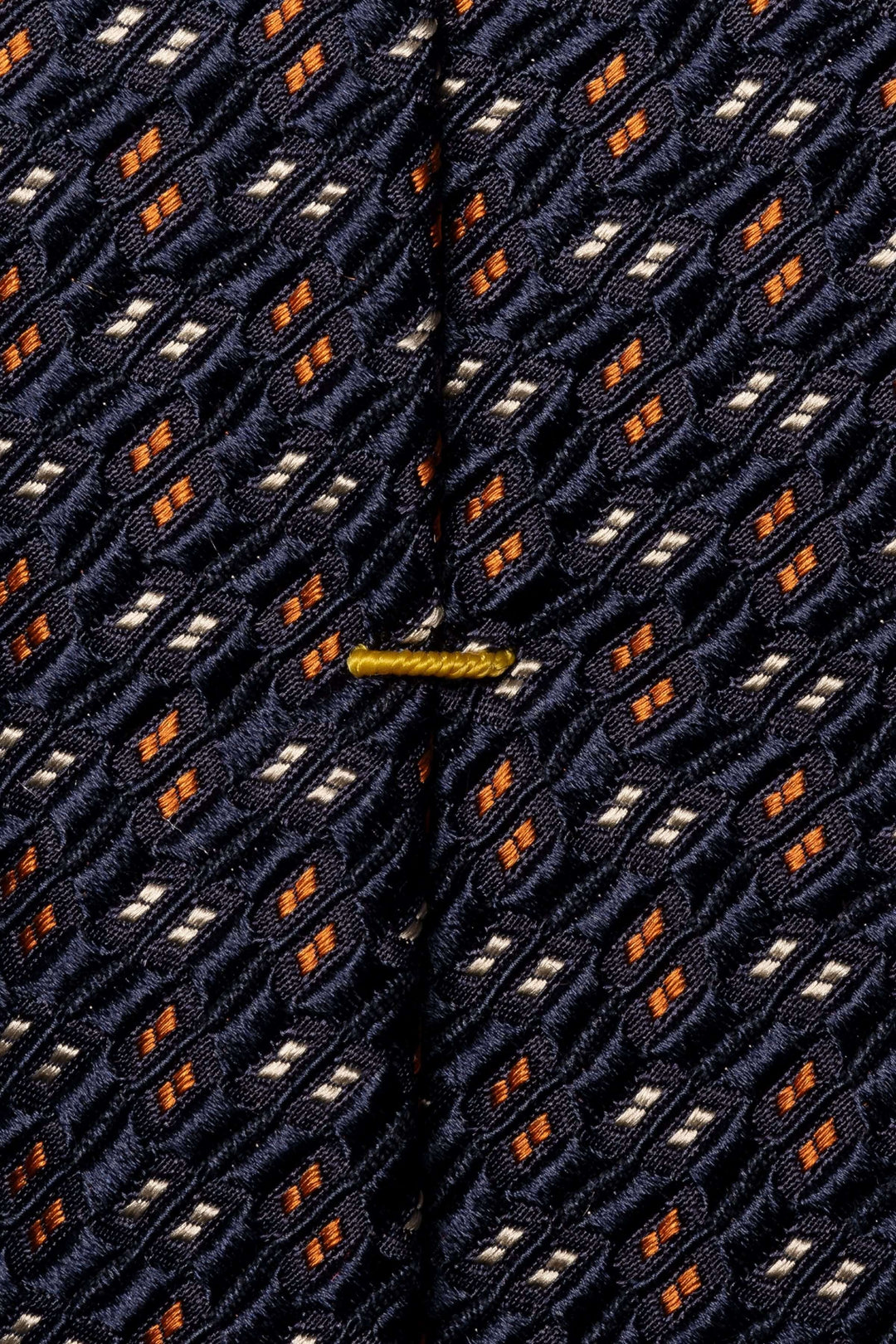 Cravate en soie avec motif géométrique en bleu navy, orange et blanc, idéal pour une tenue professionnelle.