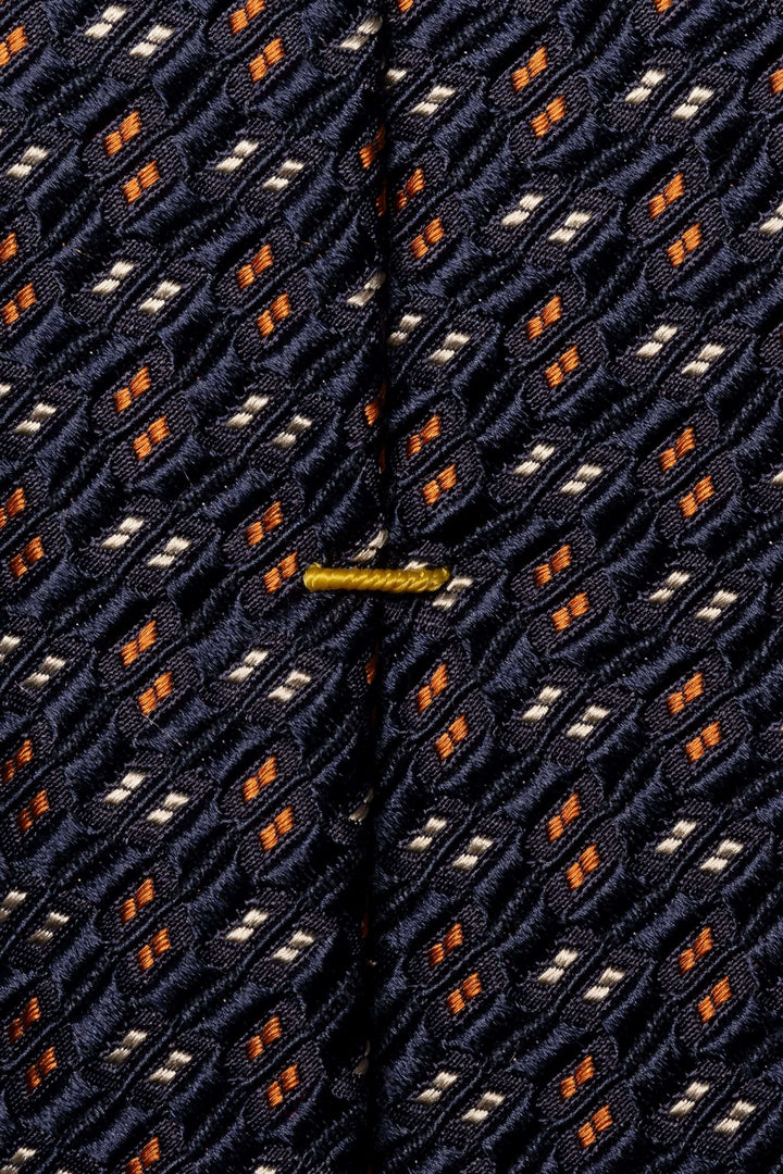 Cravate en soie avec motif géométrique en bleu navy, orange et blanc, idéal pour une tenue professionnelle.