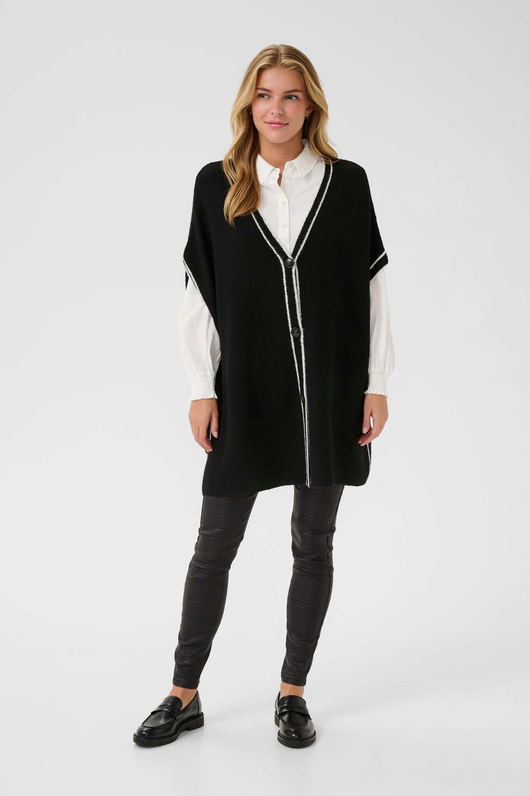 Modèle portant la Cape Rams boutonnée en tricot à bord contrastant, élégante et chic pour un style moderne et raffiné en hiver.