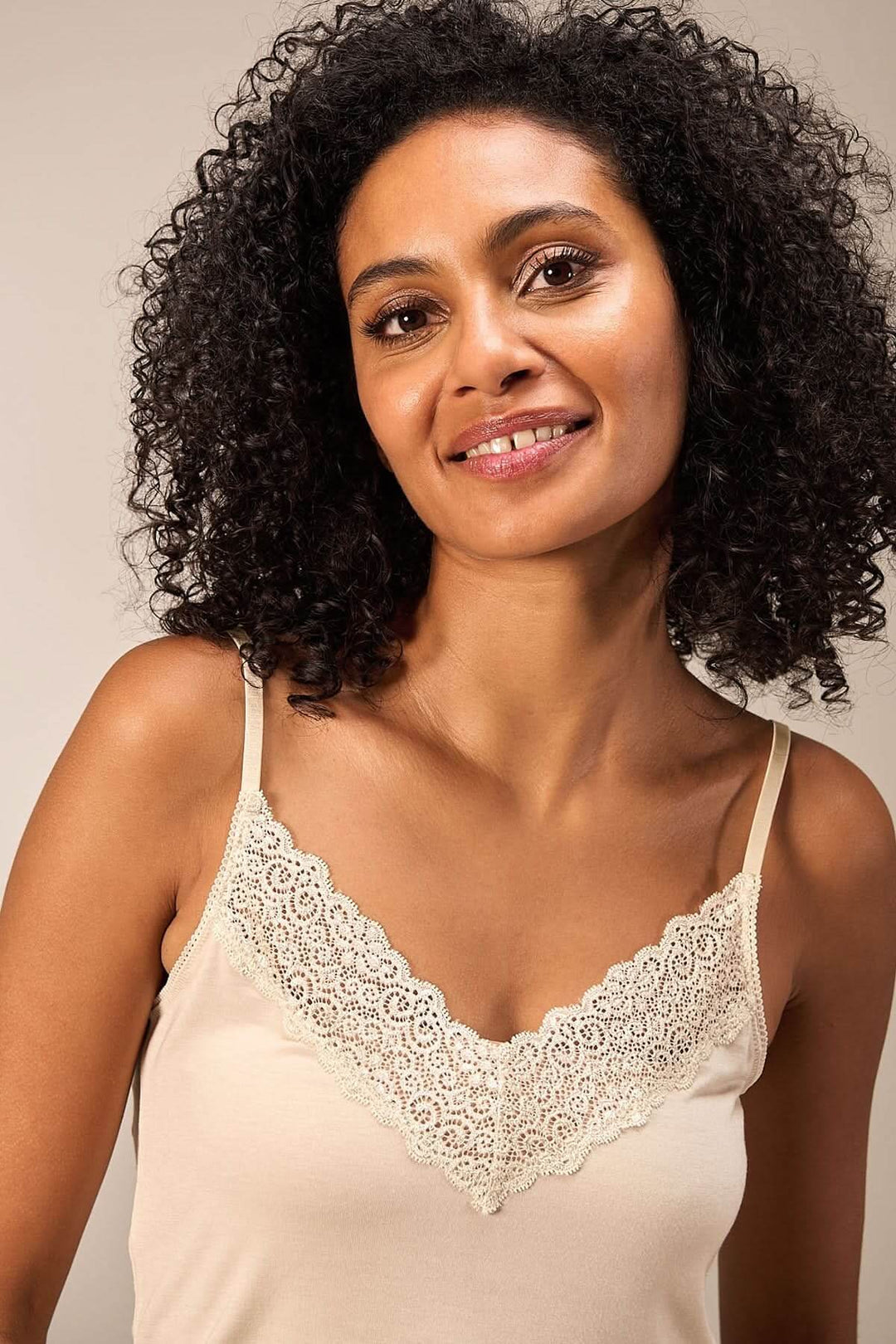 Camisole beige à fines bretelles avec encolure en dentelle, offrant confort et élégance.