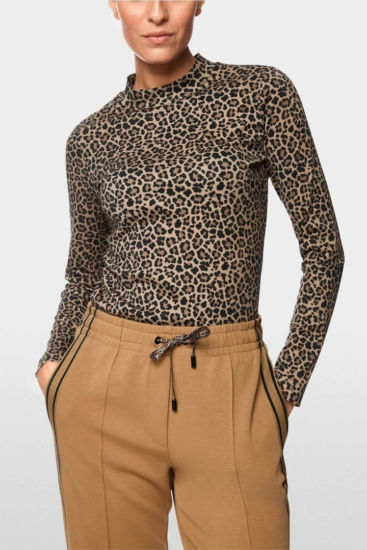 Femme portant un chandail imprimé léopard ajusté avec manches longues et col montant, combiné avec un pantalon beige, matière extensible.