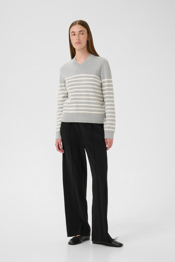 Chandail Wallis en maille fine, rayé en V, porté avec un pantalon noir pour un look chic.