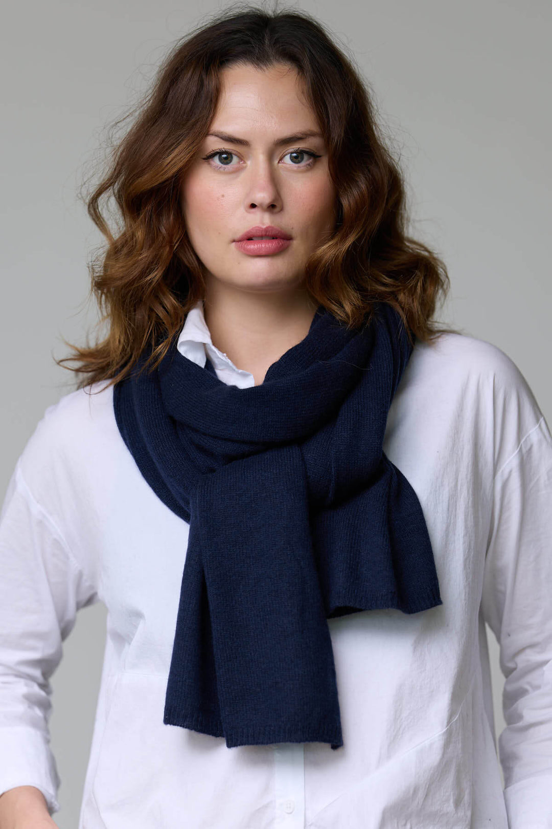 Foulard en laine bleu foncé enroulé autour du cou d’une femme, ajoutant chaleur et élégance aux tenues automnales et hivernales.
