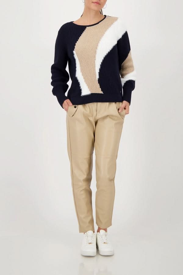 Femme portant un chandail en maille à motif graphique, col rond, coupe droite, avec un pantalon beige, style moderne et audacieux.