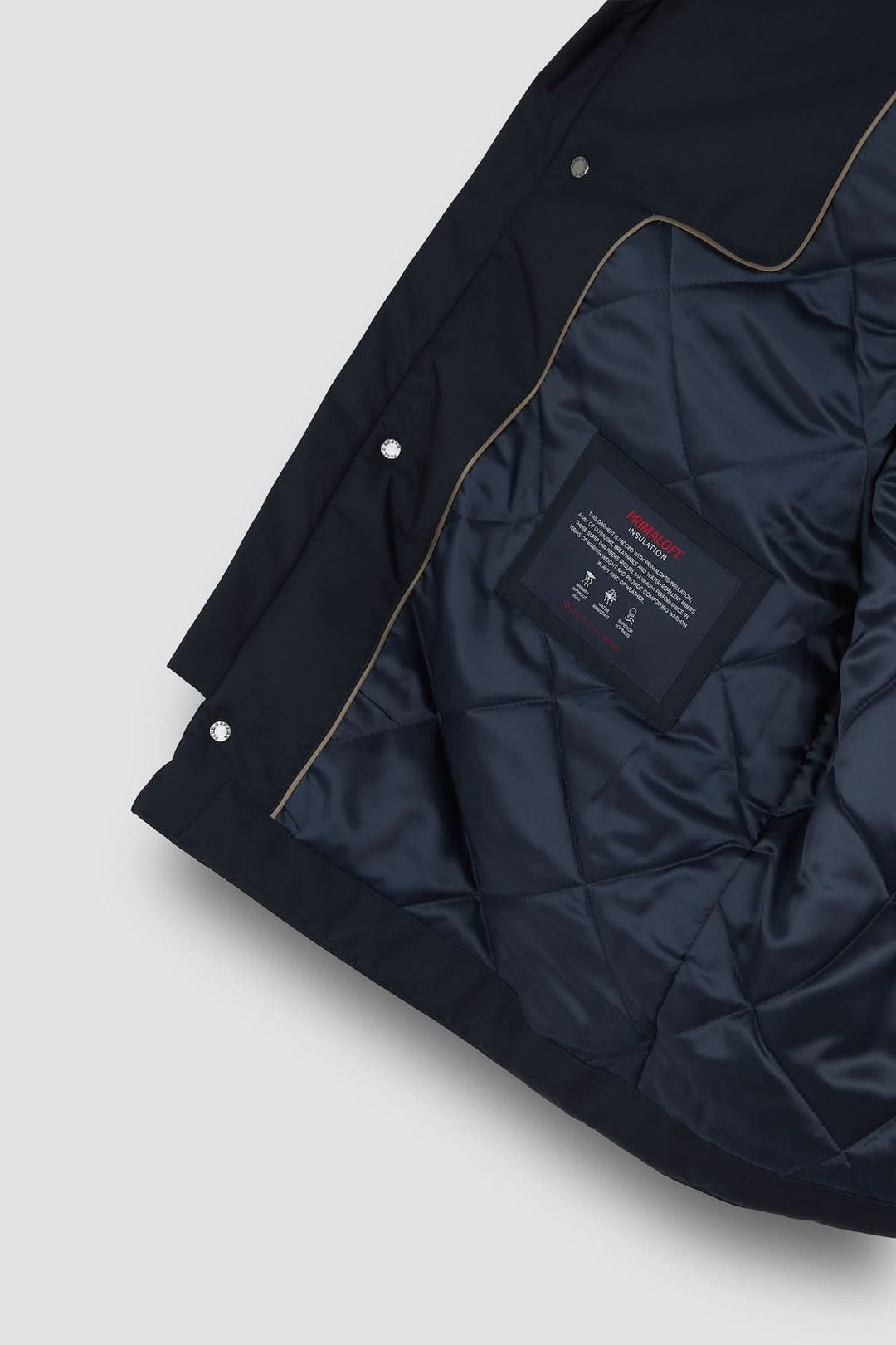 Doublure intérieure d'un manteau matelassé avec étiquette, couleur bleue, design élégant et technique.