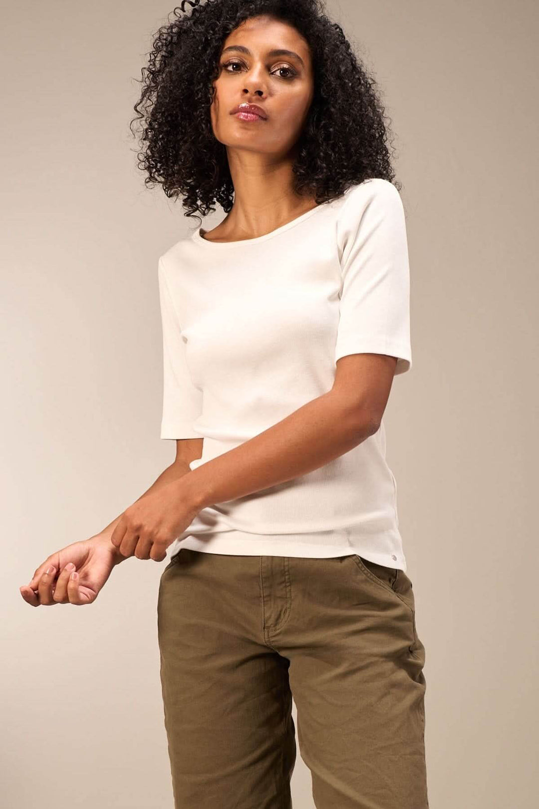 Chandail minimaliste à manches courtes, coupe ajustée, porté avec un pantalon beige, style simple et élégant.