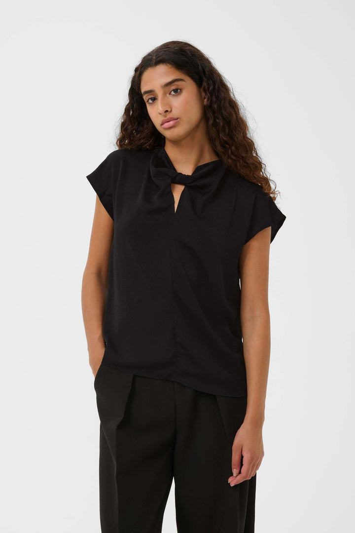 Blouse Danni fluide à col nœud en noir, légère et élégante, avec manches courtes et col effet nœud, parfaite pour un look chic et moderne.