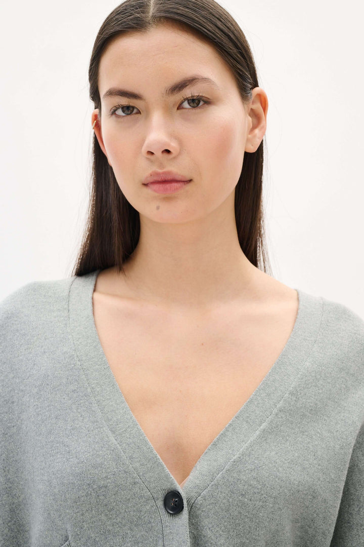 Femme portant un cardigan gris Tenley au design minimaliste avec encolure en V et boutons contrastants.