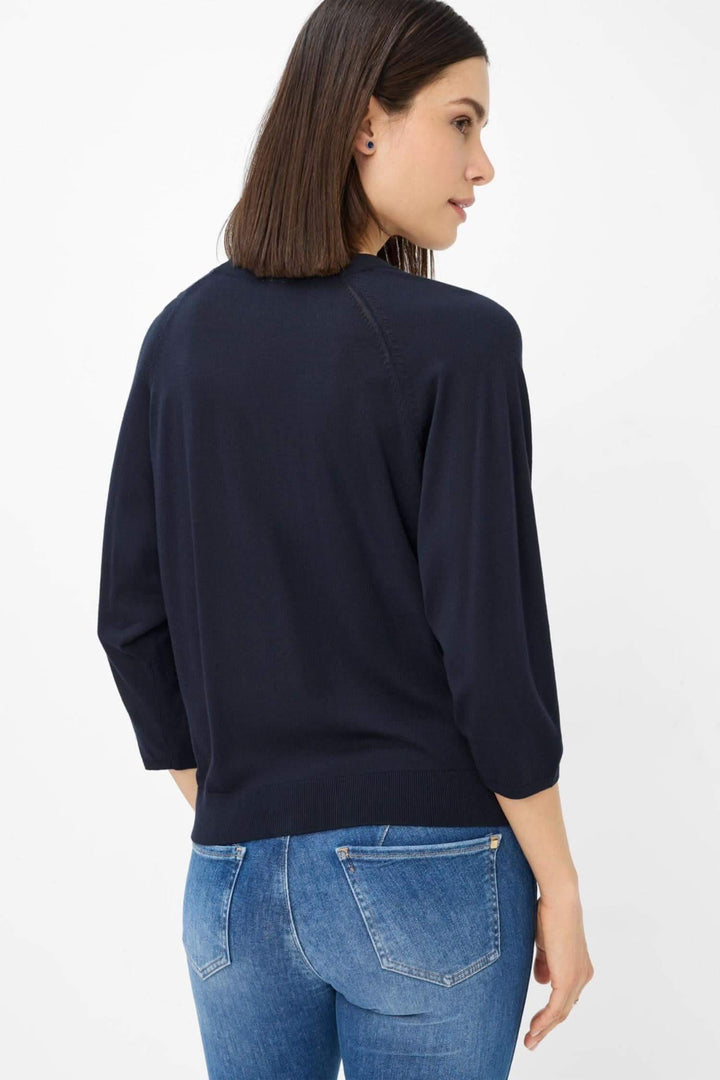 Femme portant un cardigan navy en maille fine, vue de dos, avec un jean ajusté, montrant une silhouette élégante.