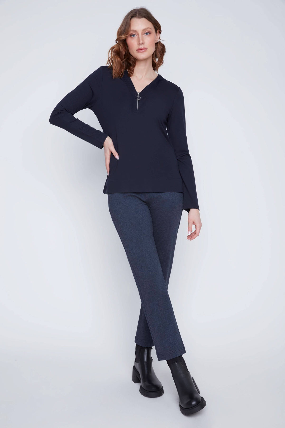 Chandail encolure en V zippée, manches longues, style décontracté, porté avec pantalon ajusté.