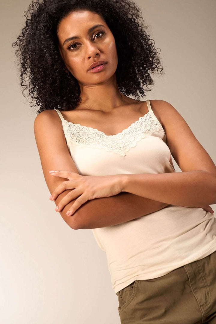 Camisole en beige avec dentelle délicate, fines bretelles, coupée près du corps, pour un look élégant et confortable.