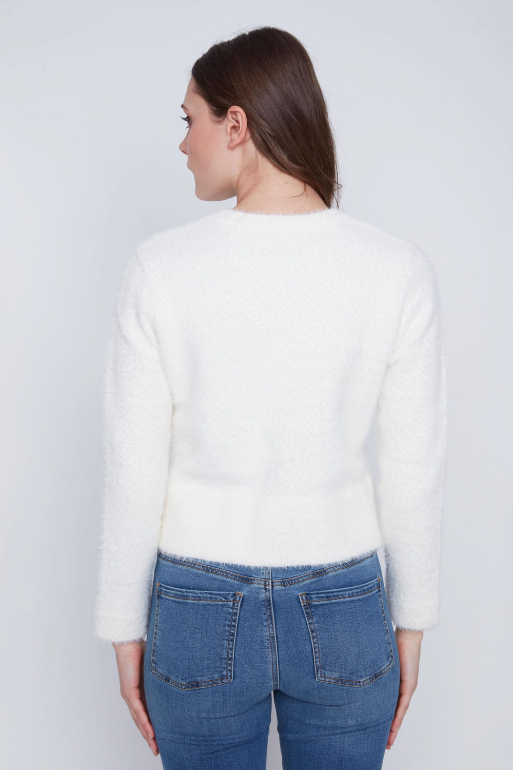 Femme de dos portant un cardigan doux blanc, coupe courte ajustée, associé à un jean.