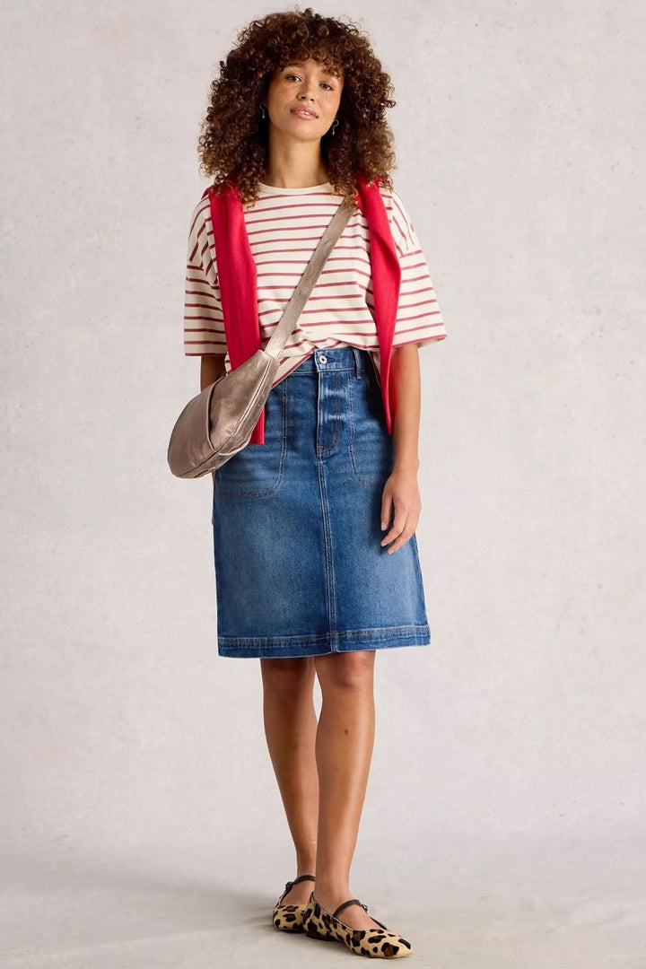 Jupe Tia en denim, coupe droite, taille haute, portée avec t-shirt rayé et accessoires tendance, look casual chic.