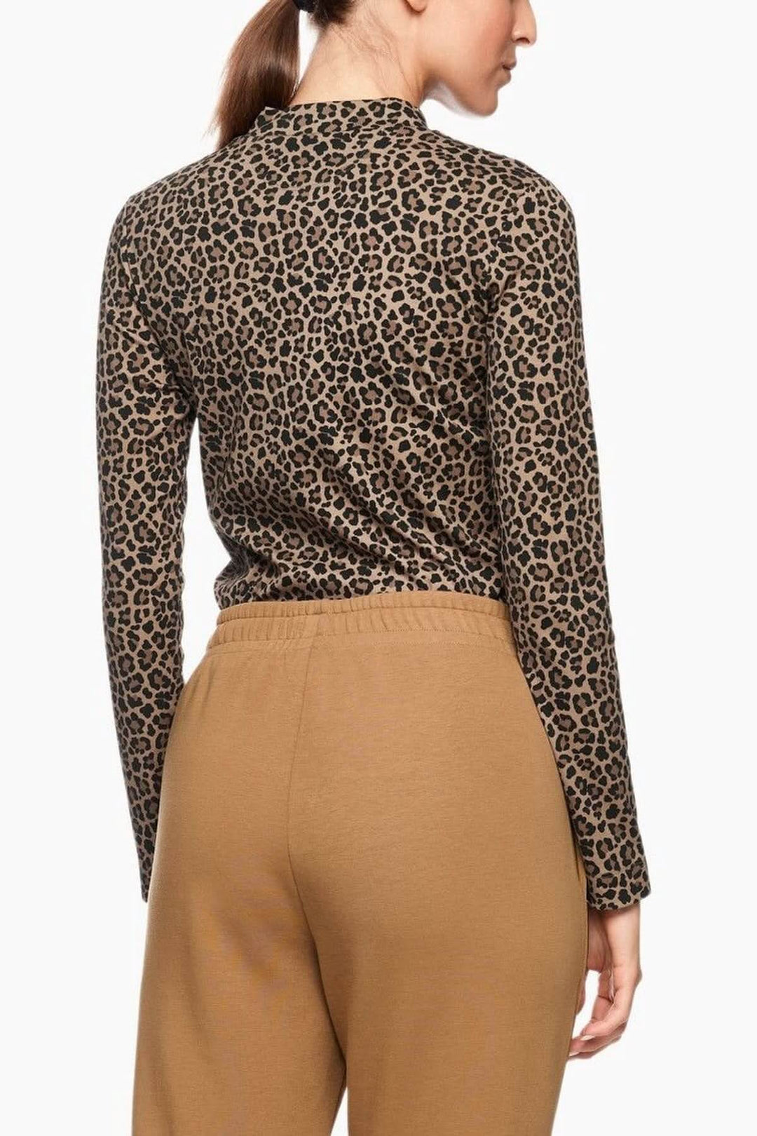 Femme portant un chandail imprimé léopard à manches longues et col montant, combinaison élégante avec un pantalon uni.