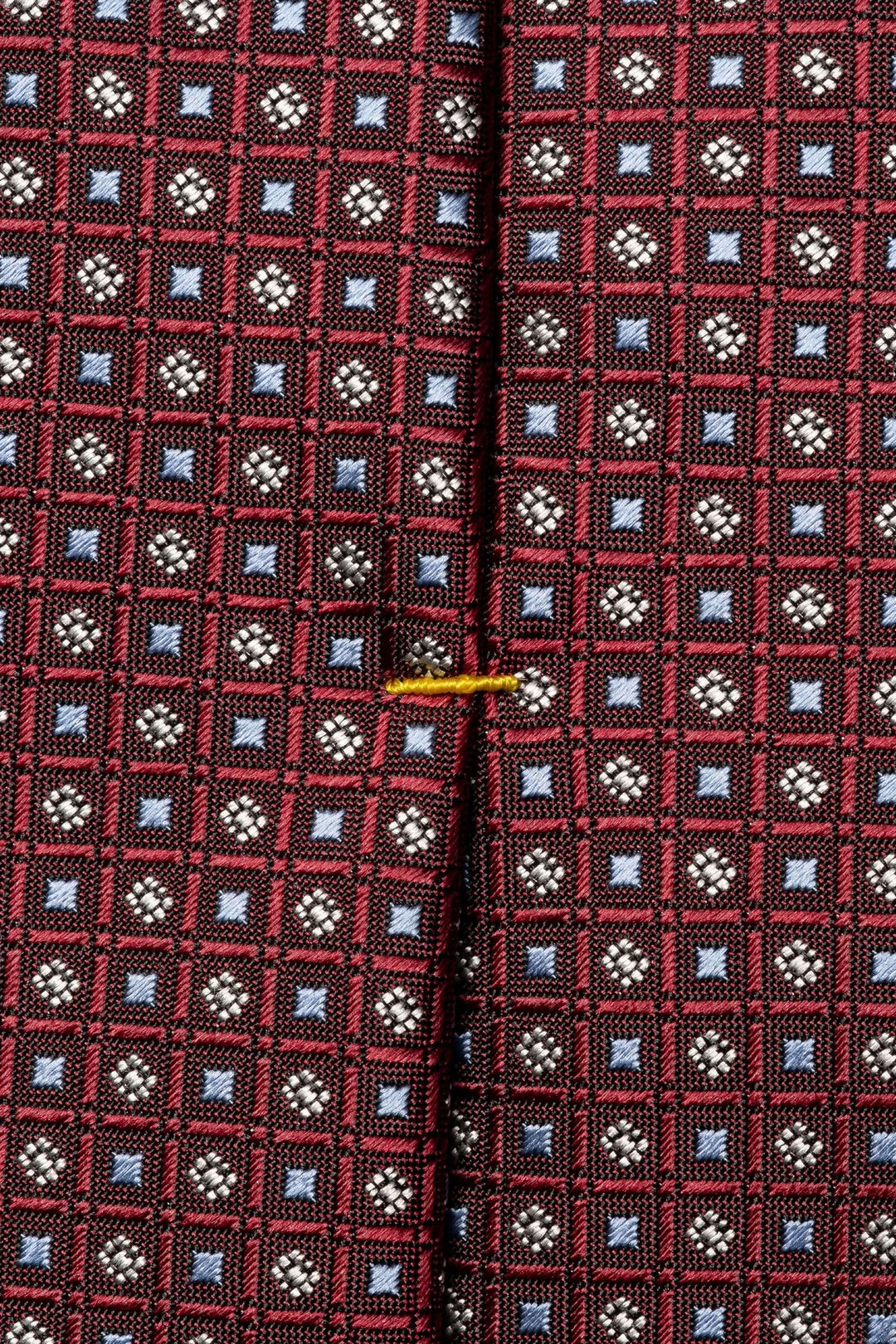 Cravate motif géométrique en rouge et bleu, texture satinée avec détails raffinés, idéale pour une tenue formelle.