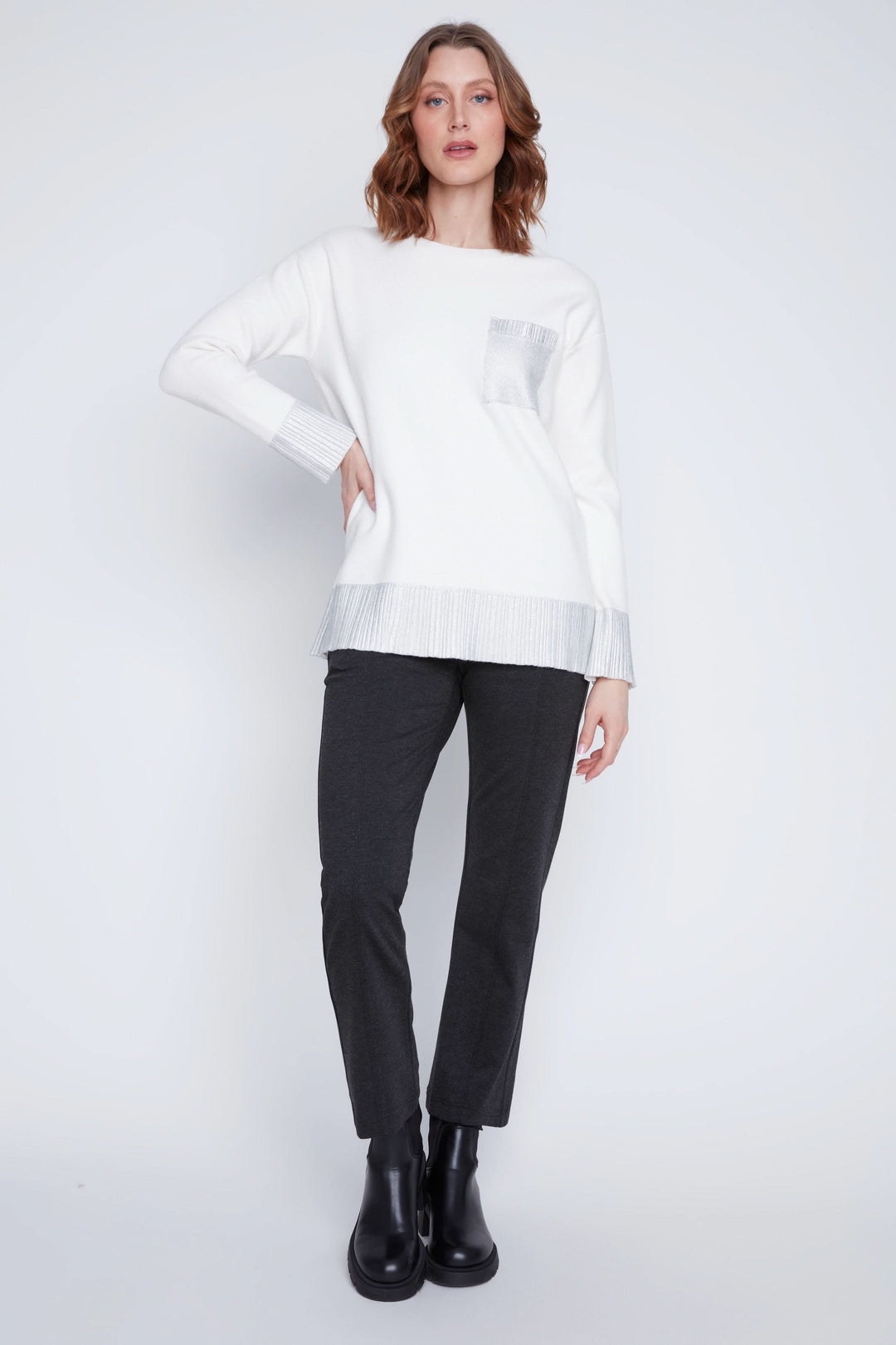 Chandail à manches longues blanc avec détails métallisés, porté avec un pantalon noir.