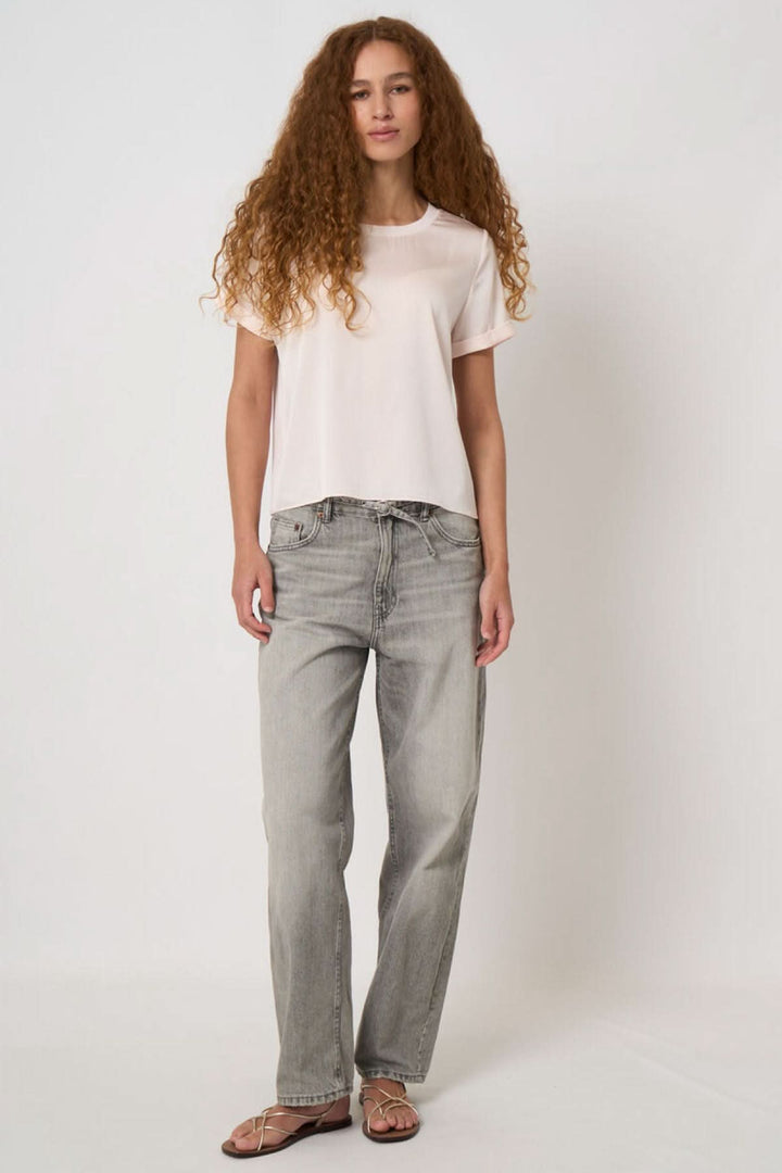 Person wearing white t-shirt and grey jeans standing in neutral pose