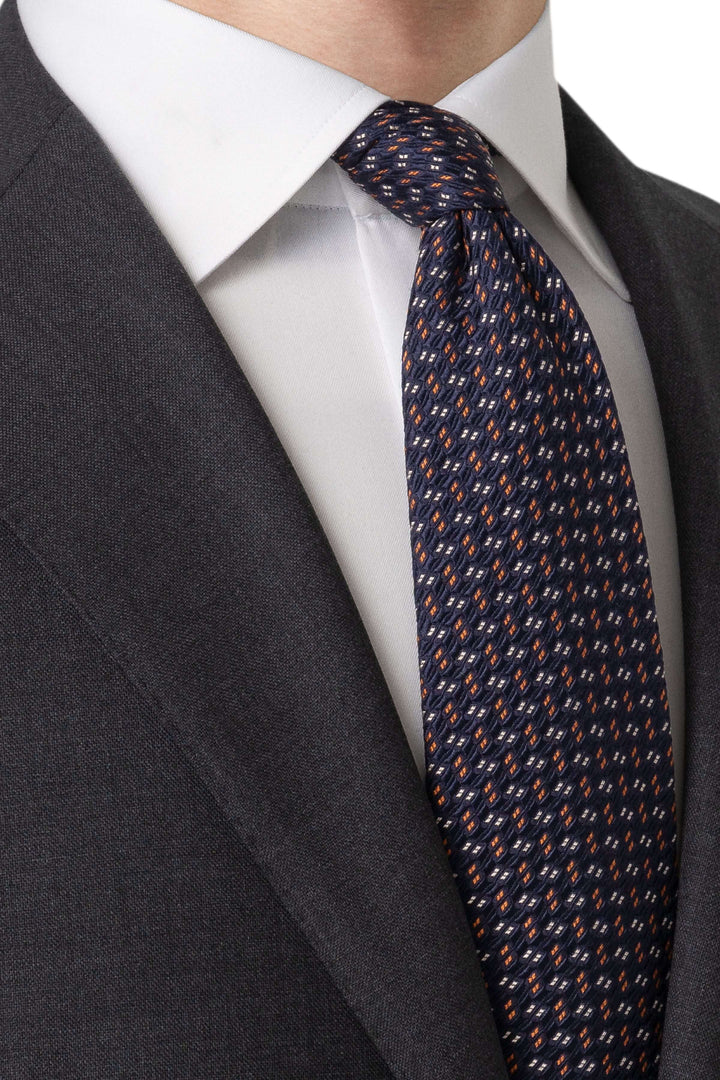 Cravate en soie avec motif géométrique, portée sur une chemise et costume pour un look professionnel élégant.