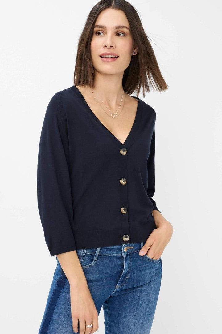 Cardigan Anique navy bleu avec encolure V profonde et patte de boutonnage, porté avec jean ajusté.