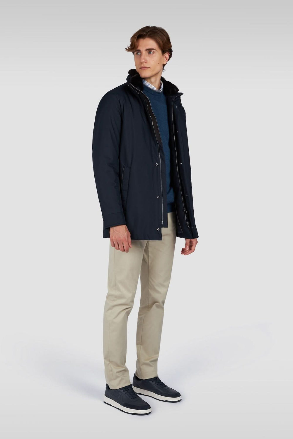 Homme portant un manteau matelassé noir avec col montant, pantalon beige et chaussures en cuir, style urbain.