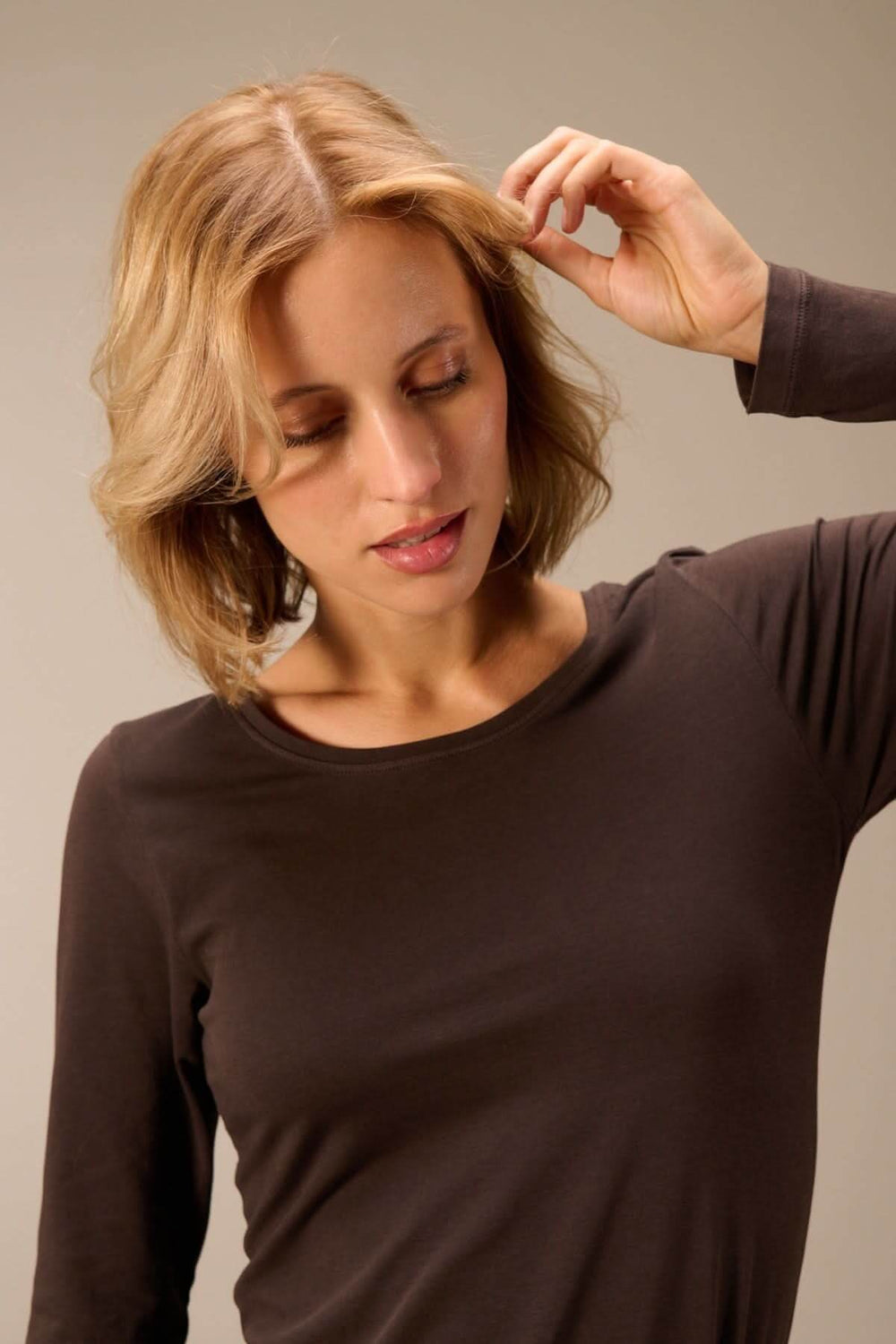 Femme portant un t-shirt manches longues col rond — jersey doux extensible en brun, style décontracté élégant pour un look versatile.