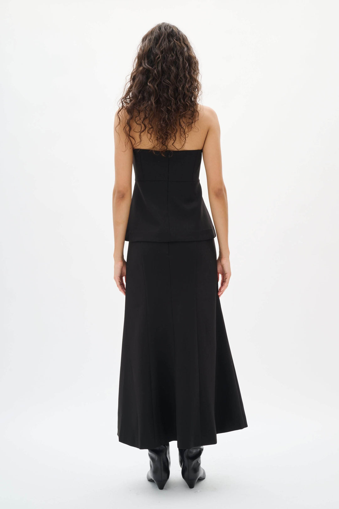 Femme en Camisole Zoeh bustier structurée noire, sans bretelles, coupe ajustée, de dos, tenue élégante et minimaliste parfaite pour occasions habillées.
