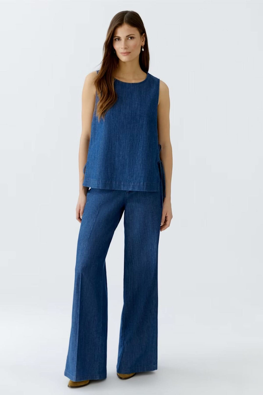 Pantalon en denim à jambe large porté avec un top assorti, offrant une élégance décontractée et moderne.