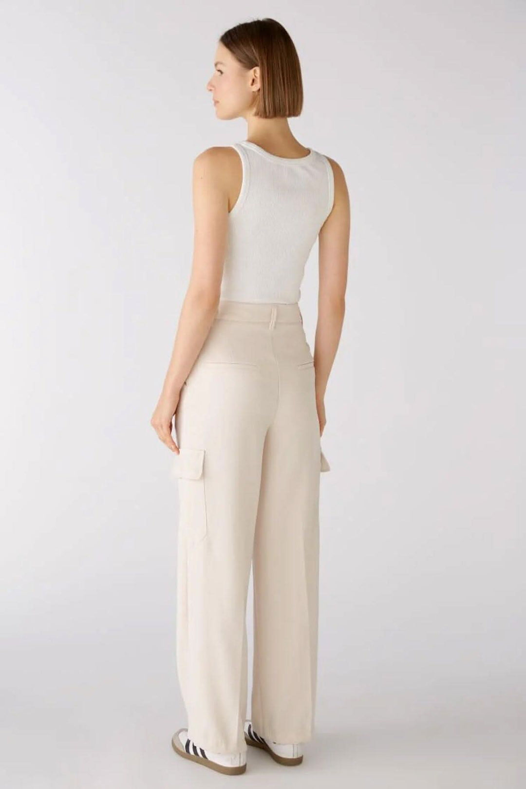 Femme vue de dos portant un pantalon cargo large beige avec un débardeur blanc.