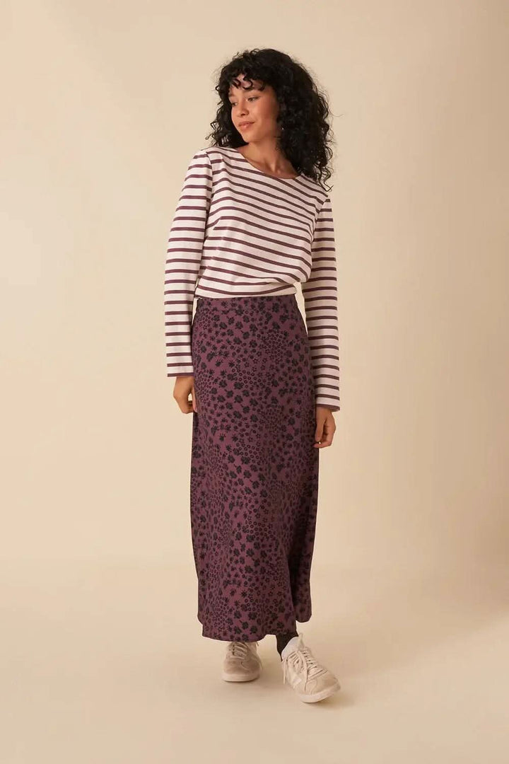 Femme portant un chandail marinière rayé avec une jupe longue à motifs violets.