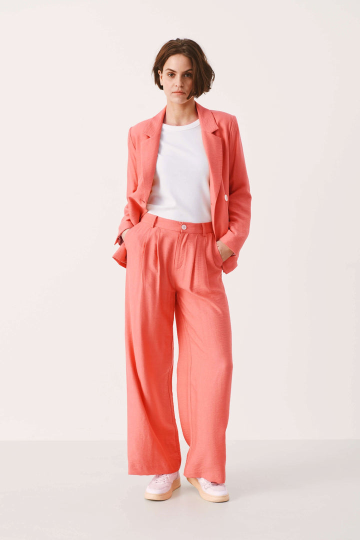 Veston Talena en rose, coupe décontractée, associé à un pantalon large et un t-shirt blanc. Élégance moderne.